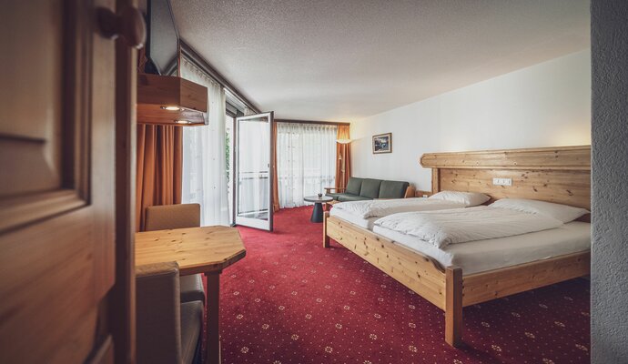 Grosses Zimmer mit Doppelbett, Balkon und rotem Teppich  | © Davos Klosters Mountains 