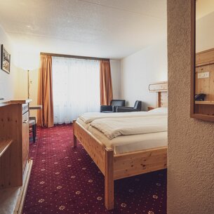 Zimmer mit Doppelbett, grossen Fenstern und Gardinen  | © Davos Klosters Mountains 