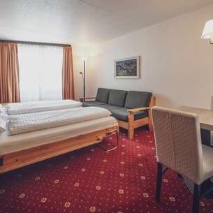 Zimmer mit Doppelbett, Sofa und Esstisch  | © Davos Klosters Mountains 