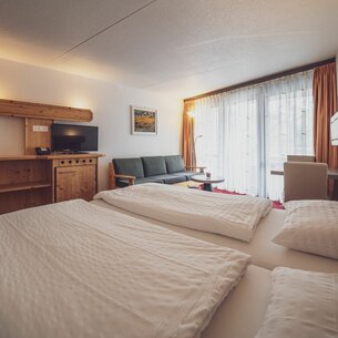 Zimmer mit Doppelbett, Sofa und Salontischchen  | © Davos Klosters Mountains 