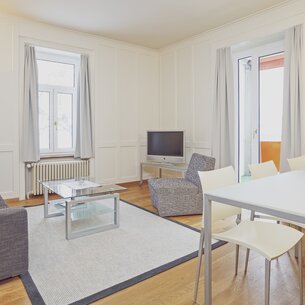 Helle Wohnung mit Fenstern, Vorhängen, Couchsessel, Couchtisch und Esstisch mit Stühlen  | © Davos Klosters Mountains 